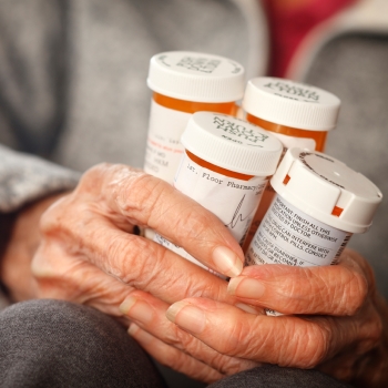 Elderly holding bottles of prescription pills in both hands
